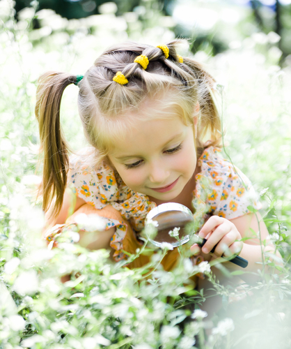 girl looking at flowers magnifying glass